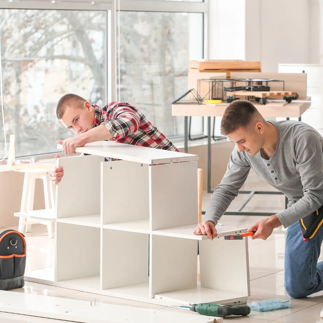 Two people assembling a white shelving unit