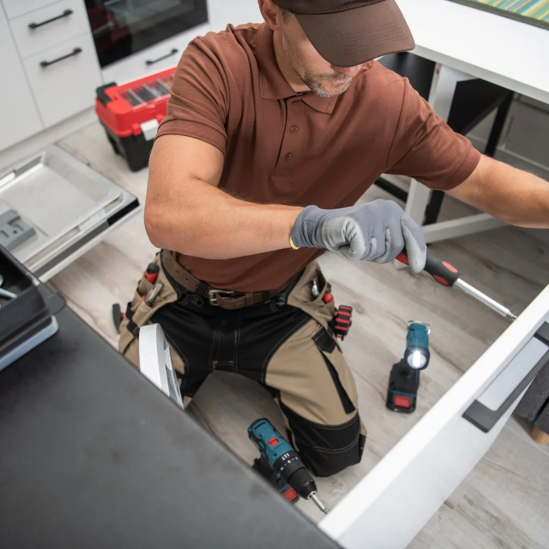 Handyman installing a drawer in a kitchen cabinet