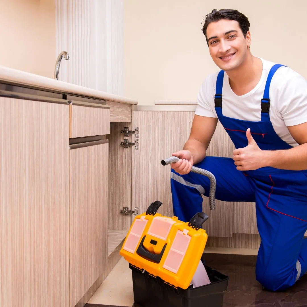Handyman with a toolbox at a sink cabinet
