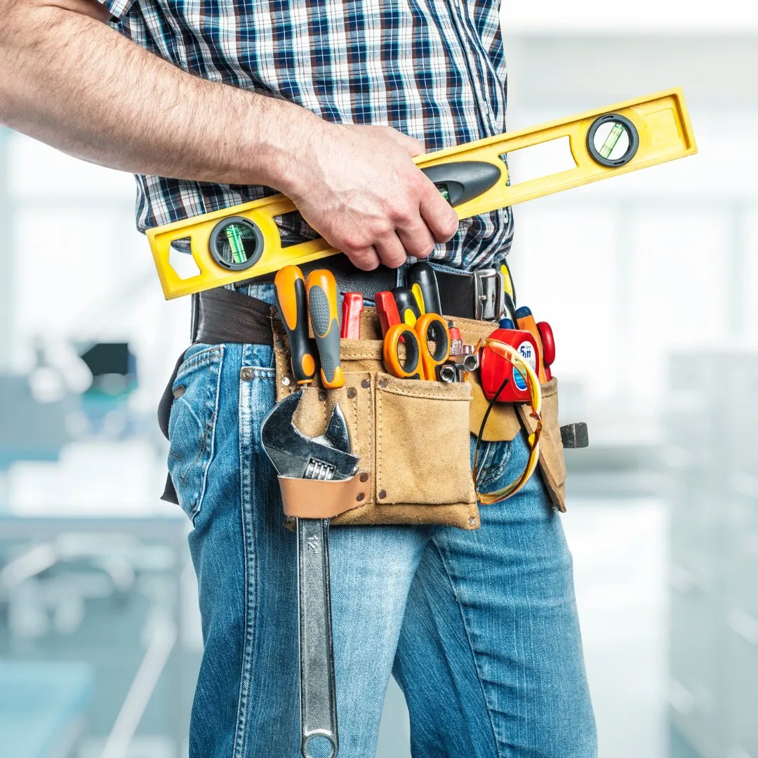 Handyman with a tool belt holding a level