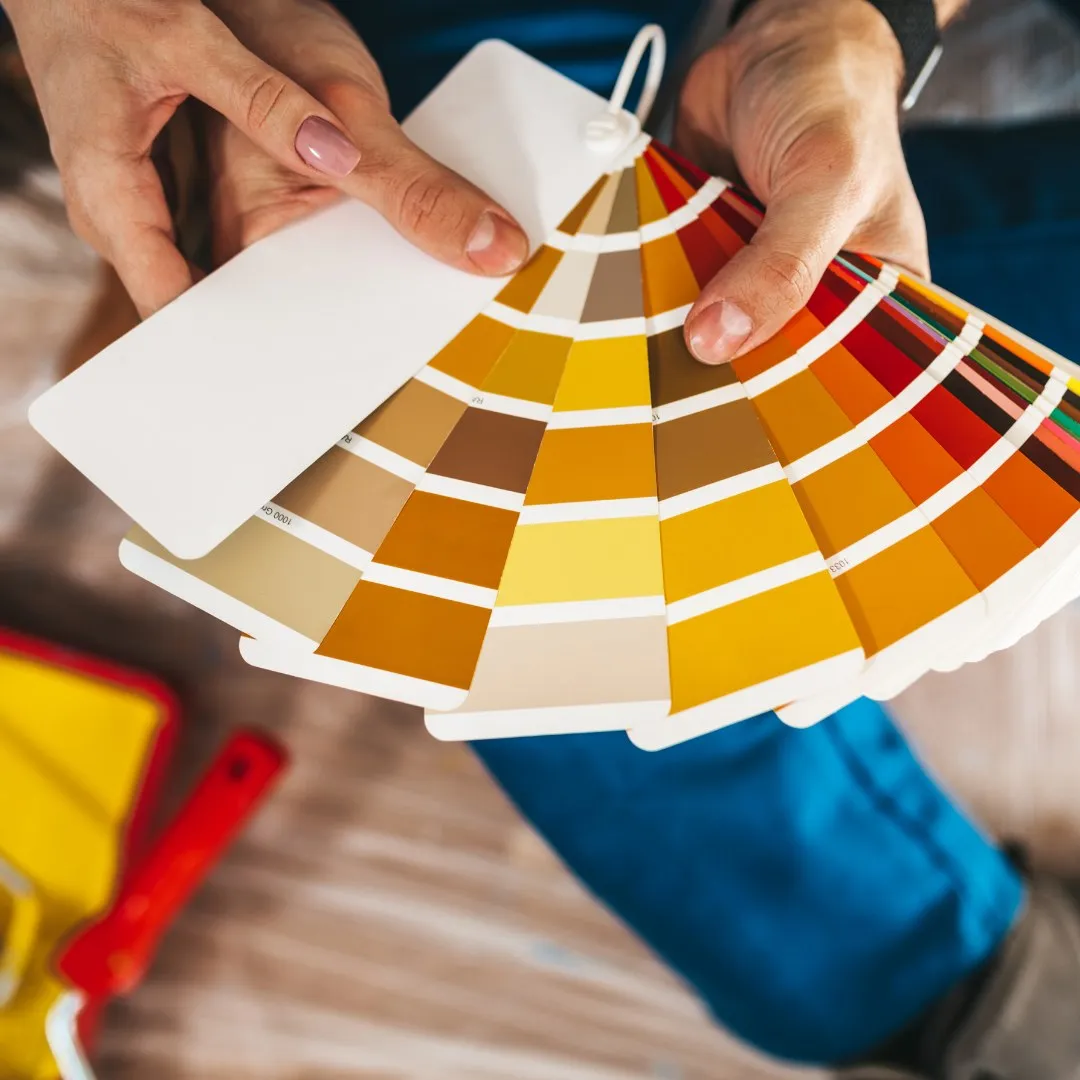 Hands holding a fan of paint color swatches