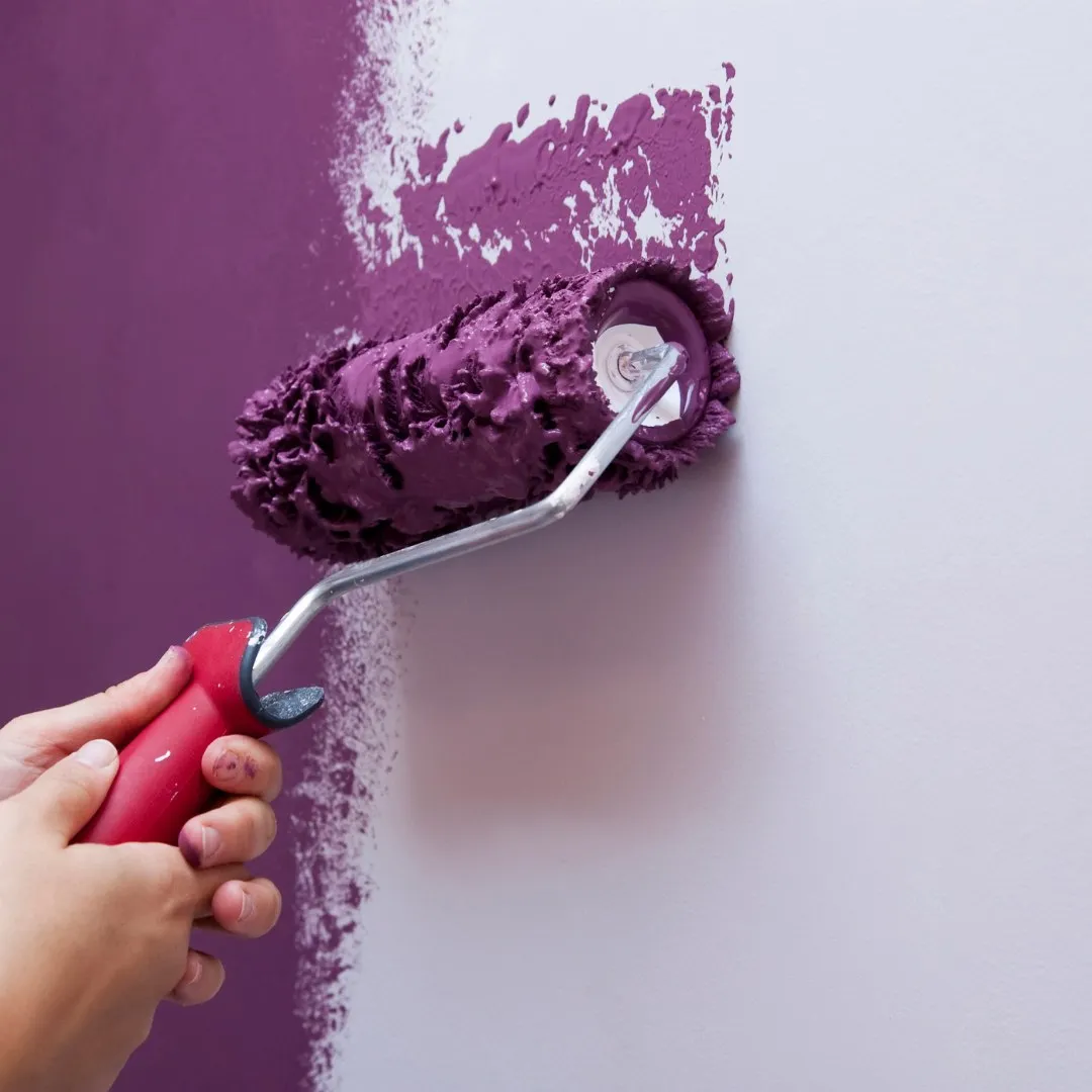 Roller painting a wall purple