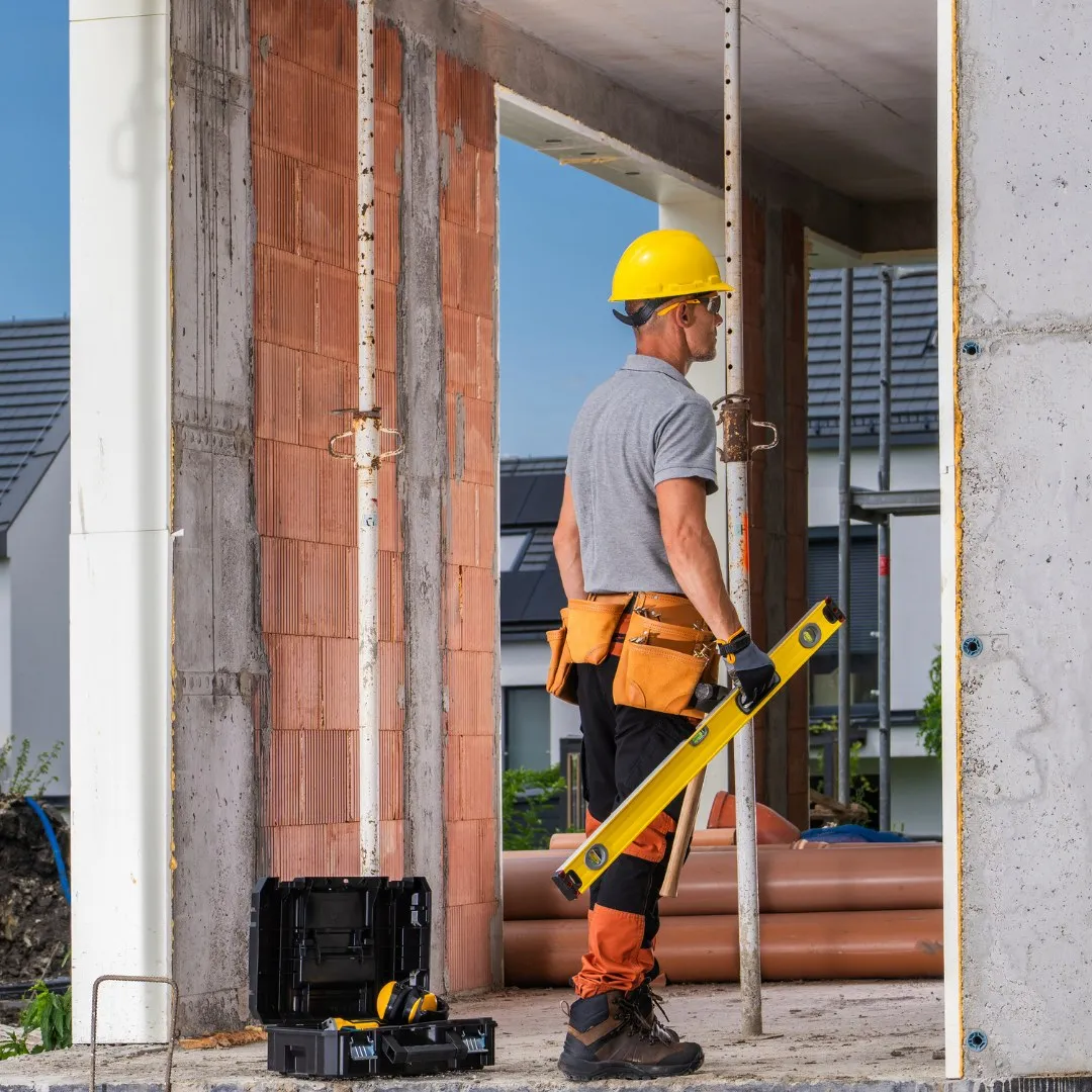 Worker carrying a level next to a toolbox